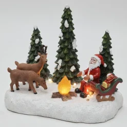 Père Noël et ses rennes au coin du feu lumineux village